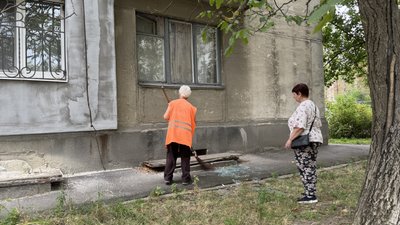 Комунальниця прибирає скло Комунальниця прибирає скло