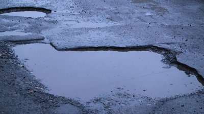 Дорога вкрита ямами, які після дощу повні води. Дорога вкрита ямами, які після дощу повні води.