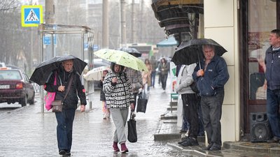 Люди з парасольками йдуть під дощем