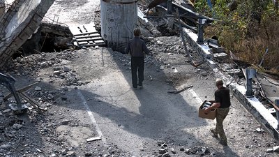 Чоловіки несуть гуманітарну допомогу зруйнованим мостом у село Богородичне на Донеччині Чоловіки несуть гуманітарну допомогу зруйнованим мостом у село Богородичне на Донеччині