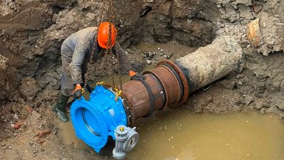Працівник облводоканалу лагодить мережу