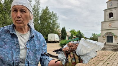 Жінка показує залишки БпЛА, який вдарив по церкві у прифронтовому селі Покровської громади