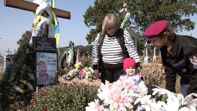Любов Головчак з двома доньками на могилі чоловіка