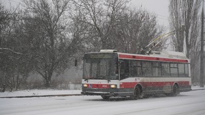 Тролейбус їде по дорозі під час снігопаду в Харкові