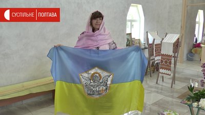Волонтерка Зоя Воронянська із прапором на якому зображений архангел Михаїл Волонтерка Зоя Воронянська із прапором на якому зображений архангел Михаїл