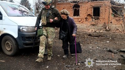 Поліцейський у Дружківці на Донеччині веде жінку до евакуаційної автівки