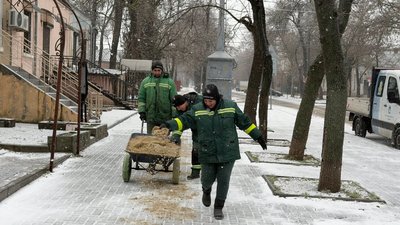 Працівники КП "Миколаївські парки" розсипають протиожеледну суміш на тротуарах Миколаєва