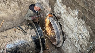 Працівник водоканалу ремонтує водогін