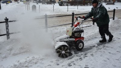Працівник комунальних служб міста із мотощіткою