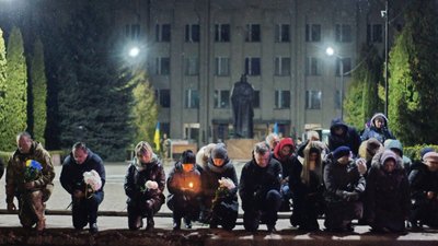 Люди на колінах зустрічають загиблого військового Люди на колінах зустрічають загиблого військового