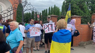 Парафіяни ПЦУ біля воріт Свято-Воскресенської церкви у Красилові тримають плакати "Геть московського попа", 25 червня 2023