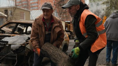 Комунальники прибирають територію двору, куди влучив російський безпілотник