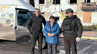 Поліцейський та волонтер евакуйовують жінку з Катеринівки