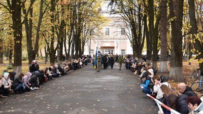 Жителі громади на колінах проводжають загиблого бійця Максима Савіцького, 26 жовтня 2023.