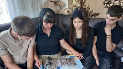 Вдова Гайка Хачатряна з дітьми розглядає фотоальбом з його фотографіями під час служби Вдова Гайка Хачатряна з дітьми розглядає фотоальбом з його фотографіями під час служби