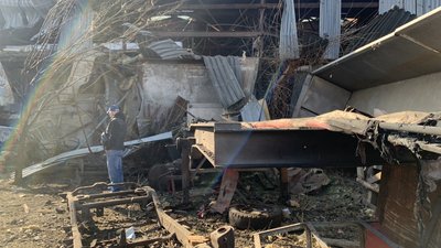 Чоловік стоїть серед уламків та пошкоджених обстрілами будівель