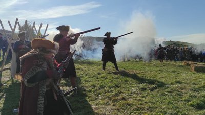 На чоловіках тодішній одяг вояк. Також чоловіки демонструють зброю, якою змагались під час битви