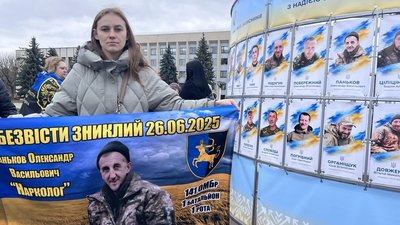 Дівчина тримає плакат із портретом Олександра Панькова