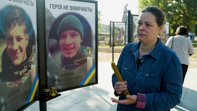 Тетяна Бутусіна поруч з пам'ятними фотографіями своїх загиблих синів у Лукашівці