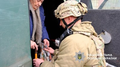 Поліцейський із "Білого янгола" допомагає жінці спуститися із евакуаційної автівки