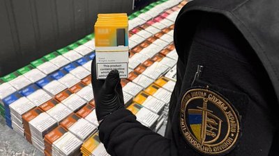 Митник тримає упаковку контрабандних картриджів для електронних сигарет