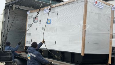 Люди вантажать генератор, який отримала Чернігівщина від Франції
