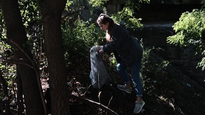 Дівчина прибирає сміття неподалік Руського мосту Дівчина прибирає сміття неподалік Руського мосту