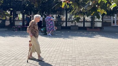 Жінка з тростиною йде вулицею
