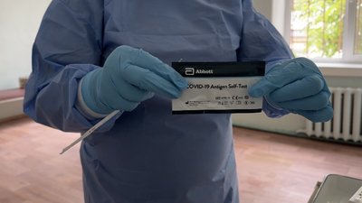 Медичний працівник у захисних рукавичках тримає набір для експрес-тесту на COVID-19