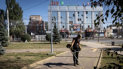 Чоловік косить траву біля розбитого торговельного центру в Краматорську