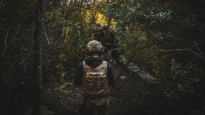 Військові на Сумщині прямують через ліс до позиції, де закріплена гаубиця підрозділу