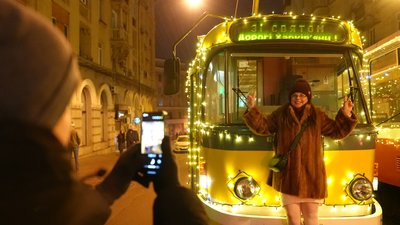 Жителька Харкова фотографується біля трамвая, прикрашеного святковою ілюмінацією