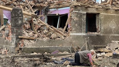 Жінка схилилася над тілом загиблого біля зруйнованого будинку 