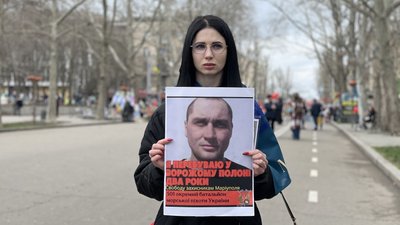 Учасниця акції Дар'я тримає плакат, на якому зображений її чоловік, під час акції-нагадування. Учасниця акції Дар'я тримає плакат, на якому зображений її чоловік, під час акції-нагадування.