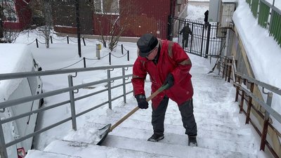 Чоловік розчищає сходи від снігу