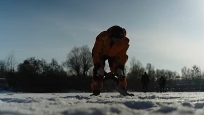 Чоловік прорізає ополонку для риби