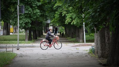 Жінка їде велосипедом вулицею у середмісті Херсона