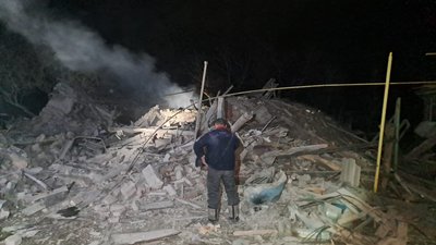 Чоловік стоїть біля зруйнованої будівлі у Куп'янському районі