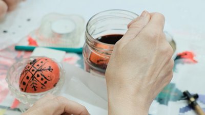 Писанку занурюють у червону фарбу Писанку занурюють у червону фарбу