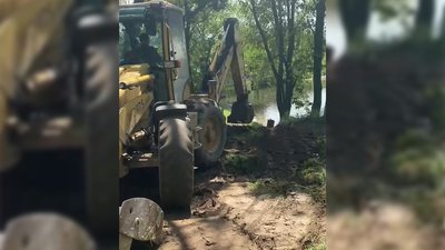 Трактор копає на березі річки Південний Буг