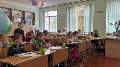 Першокласники сидять за партами у школі