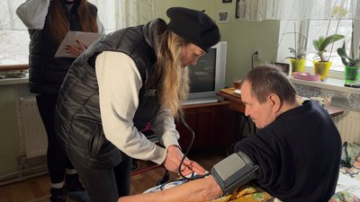 Медична сестра міряє тиск чоловіку