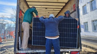Робітники розвантажують обладнання для електростанції Робітники розвантажують обладнання для електростанції