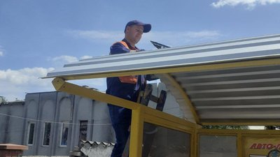 Робітник встановлює сонячні панелі на зупинці громадського транспорту. Робітник встановлює сонячні панелі на зупинці громадського транспорту.