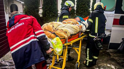 Травмовану жінку виносять рятувальники