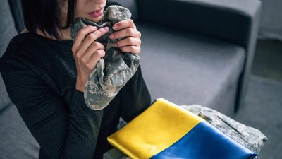 Жінка тримає кепку воїна та прапор