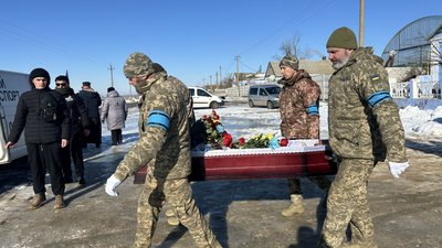 Військові несуть домовину, вкриту квітами, під час церемонії прощання