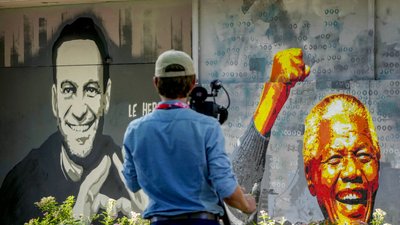 Оператор знімає фрески, на яких зображено Олексія Навального (зліва) та Нельсона Манделу у Женеві, Швейцарія, 15 червня 2021 р. Фото: АР
