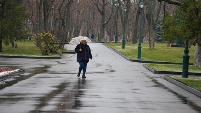 Жінка йде під дощем у харківському парку