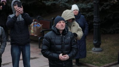 Люди дивляться на запалення свічок на менорі